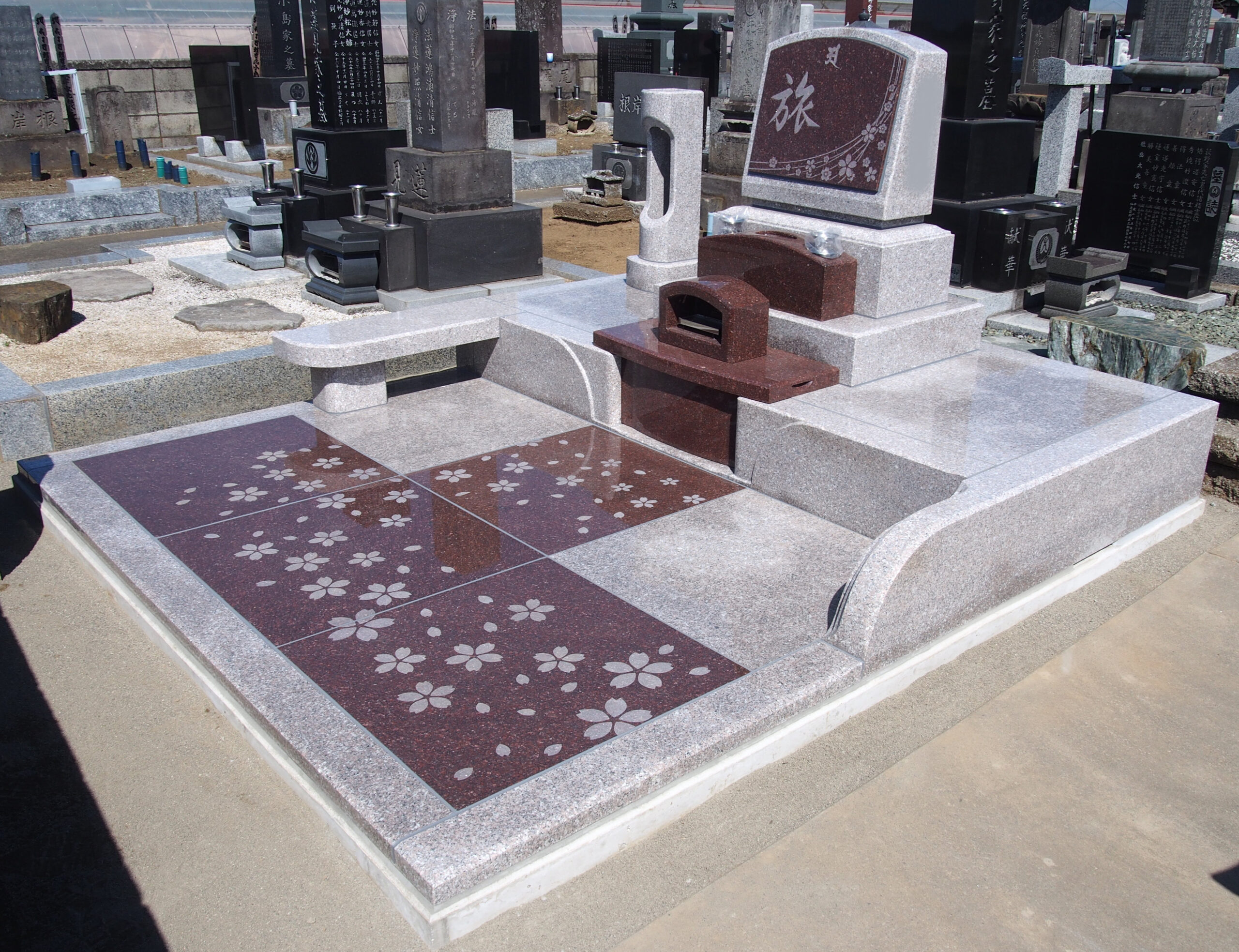 「旅」の文字と桜の花が刻まれた赤色のカラー墓石（群馬県板倉町）